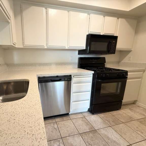 Thumbnail 26 of 31 A kitchen with a black oven and a black microwave.