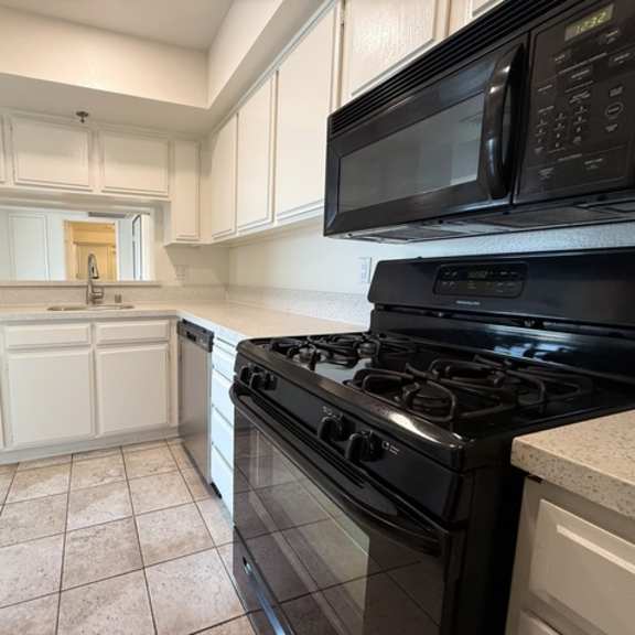 Thumbnail 23 of 31 A kitchen with black appliances and white cabinets.