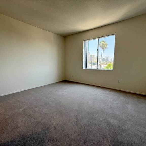 Thumbnail 29 of 31 Empty room with a window showing a cityscape outside.