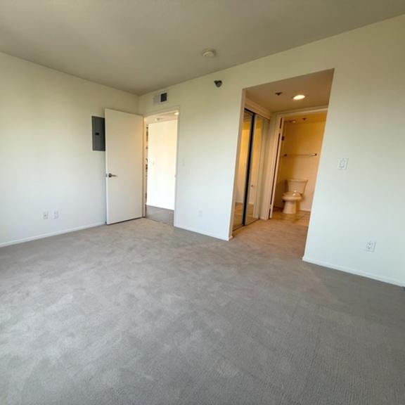 Thumbnail 28 of 31 A spacious room with a carpeted floor and two doors.
