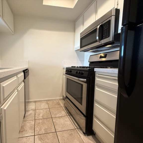 Thumbnail 12 of 28 A kitchen with black appliances and white cabinets.