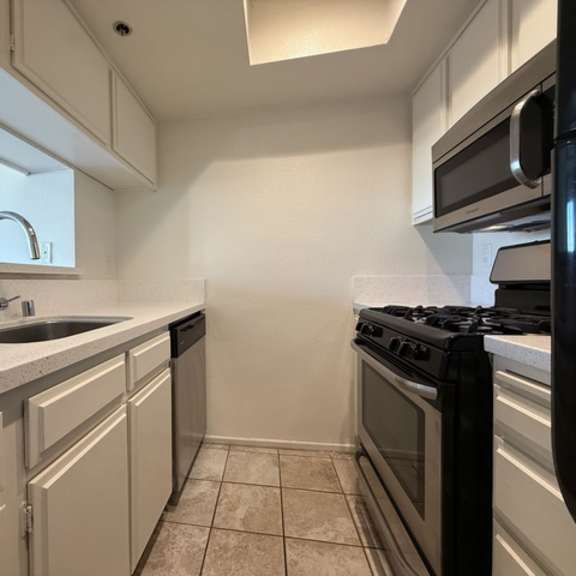 Thumbnail 19 of 28 A kitchen with a black stove top oven and white cabinets.