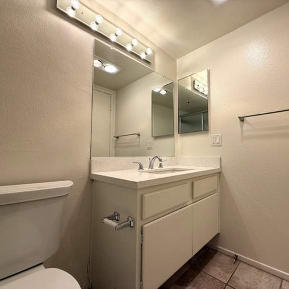 Thumbnail 14 of 28 A bathroom with a white sink and a mirror with lights above it.
