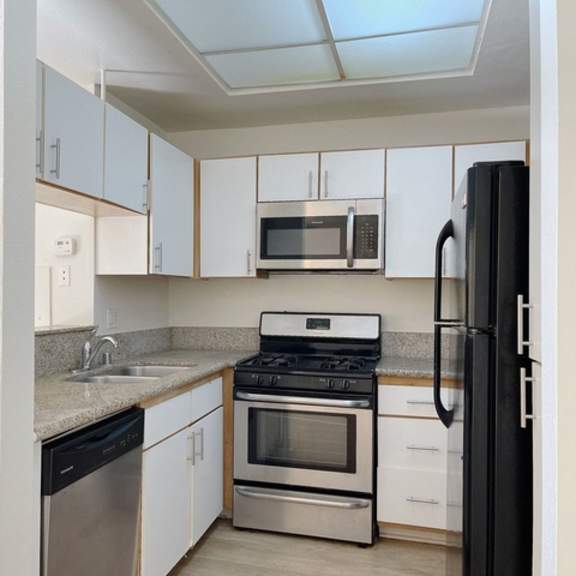 Thumbnail 7 of 16 A kitchen with white cabinets and black appliances.