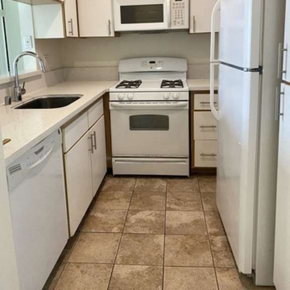 Thumbnail 2 of 54 A kitchen with white appliances and cabinets.