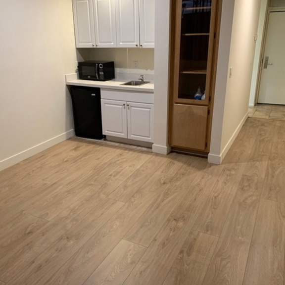 Thumbnail 2 of 5 A kitchen with white cabinets and a black trash can.