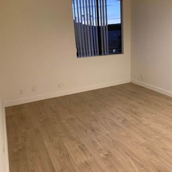 Thumbnail 3 of 5 A room with light wood flooring and a window with blinds.