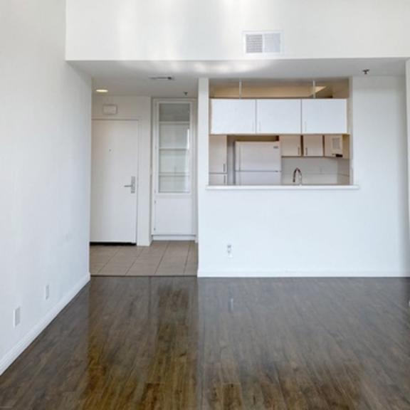 Thumbnail 3 of 22 A white room with a kitchen area in the back.