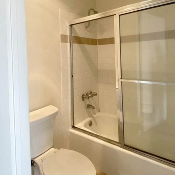 Thumbnail 14 of 22 A white toilet sits next to a bathtub in a bathroom.