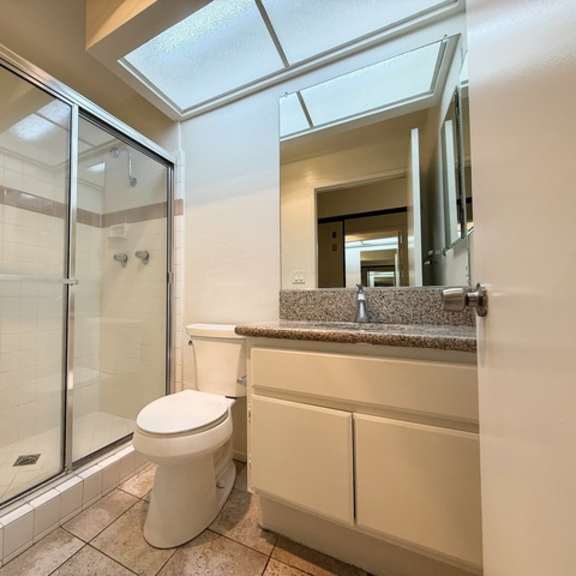 Thumbnail 4 of 13 A white toilet sits in a bathroom with a walk-in shower.