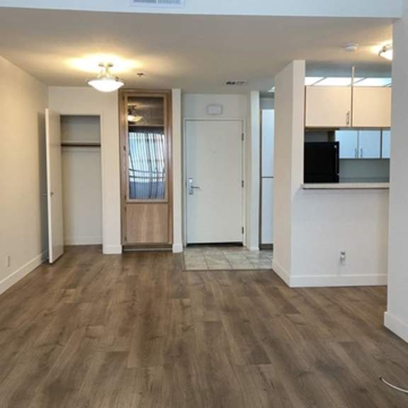 Thumbnail 7 of 8 A room with a wooden floor and white walls.