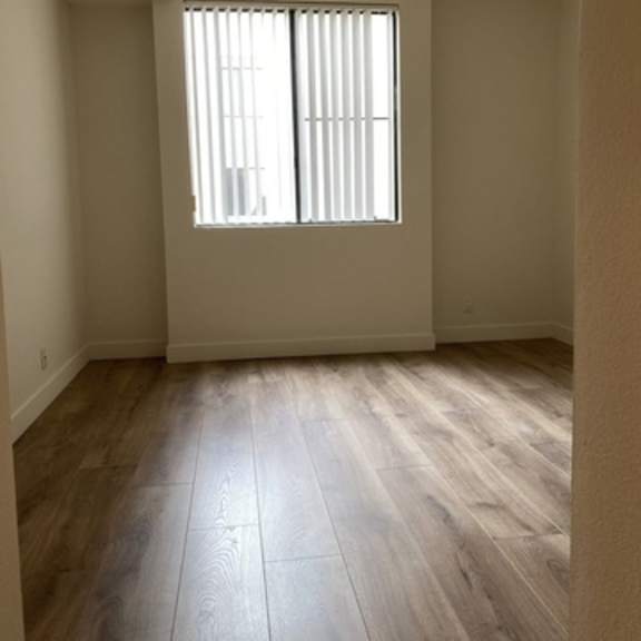 Thumbnail 6 of 8 A room with a window and wooden flooring.