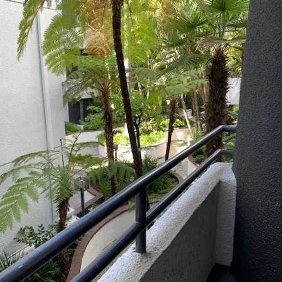 Thumbnail 6 of 19 A balcony with a metal railing and a view of a green garden.