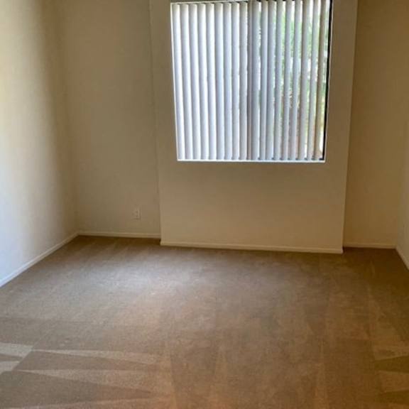 Thumbnail 19 of 19 A room with a window and a carpeted floor.