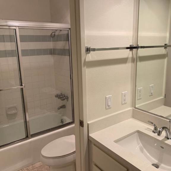 Thumbnail 5 of 8 A white toilet is next to a sink in a bathroom.