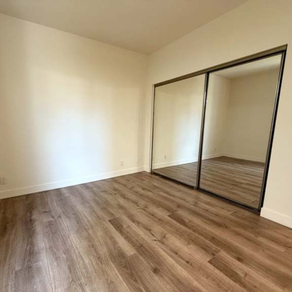 Thumbnail 21 of 44 A room with wooden flooring and a large mirror.
