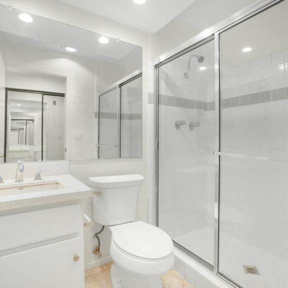 Thumbnail 3 of 7 A white bathroom with a toilet, sink, and shower.