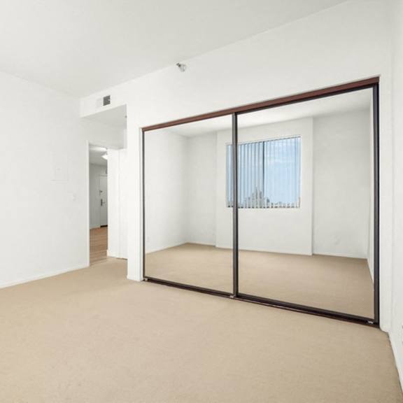 Thumbnail 9 of 39 A room with a brown carpet and a large mirror on the wall.