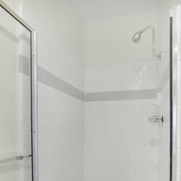 Thumbnail 21 of 39 A white tiled shower stall with a drain in the middle.