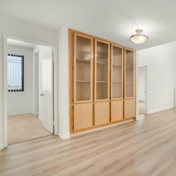 Thumbnail 16 of 39 A room with wooden floors and a large window with a view of a cityscape.