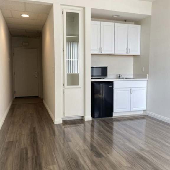Thumbnail 13 of 16 A kitchen with white cabinets and a black trash can.