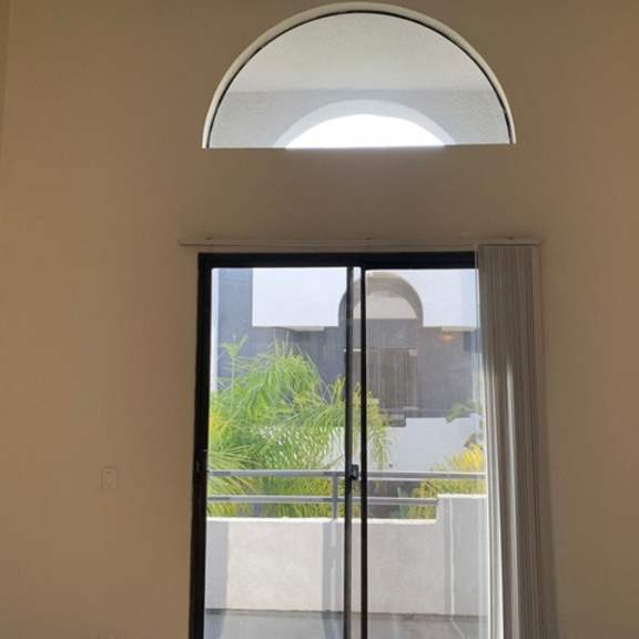 Thumbnail 12 of 30 A window with a view of a balcony and plants outside.
