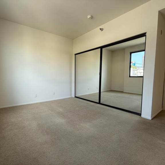 Thumbnail 35 of 44 A room with a carpeted floor and a large mirror on the wall.