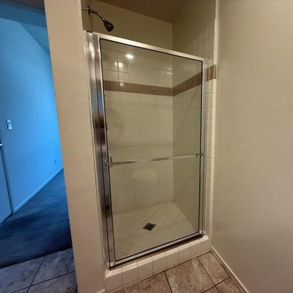 Thumbnail 34 of 44 A shower stall with a glass door is in a bathroom.