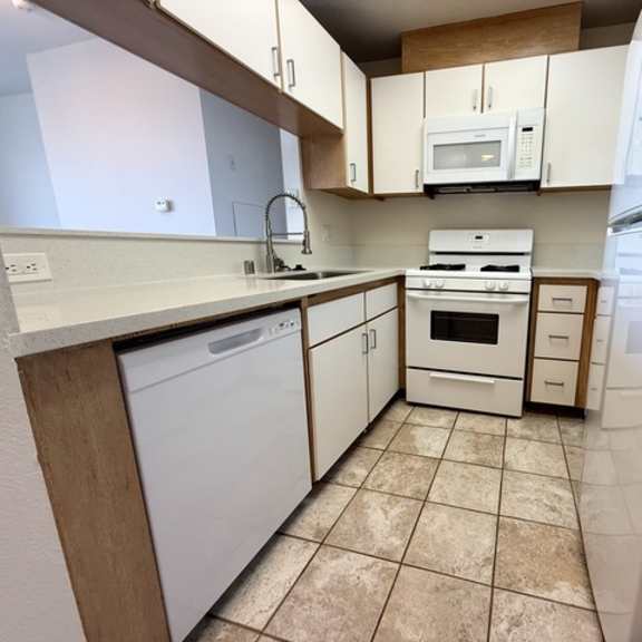 Thumbnail 3 of 54 A kitchen with white appliances and wooden cabinets.