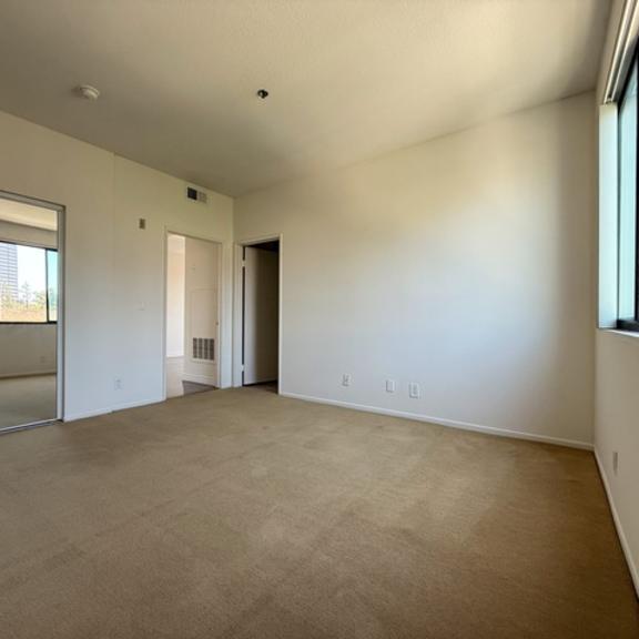 Thumbnail 34 of 54 A large empty room with a carpeted floor and a window.
