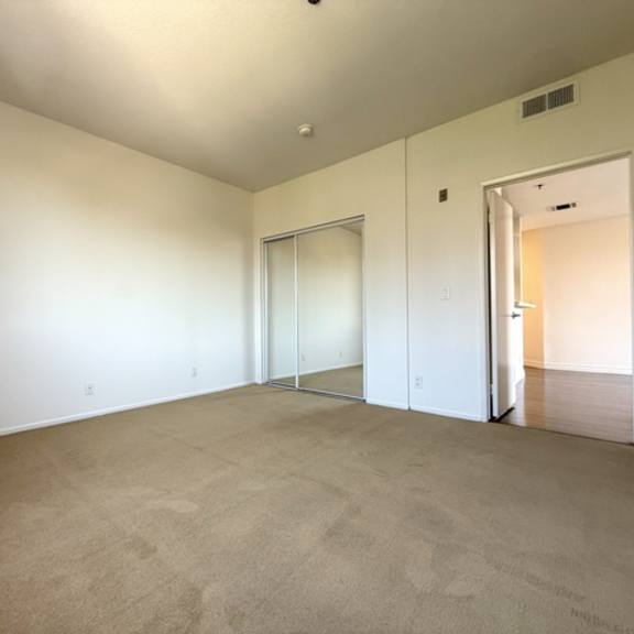 Thumbnail 27 of 54 A large, empty room with carpeted flooring and white walls.