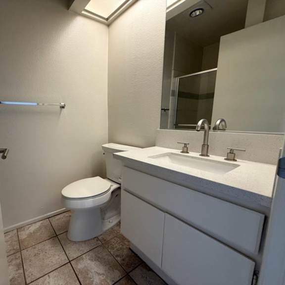 Thumbnail 40 of 54 A white bathroom with a toilet, sink, and mirror.
