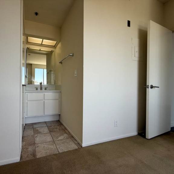 Thumbnail 37 of 54 A bathroom with a white vanity and a mirror is visible from a hallway.