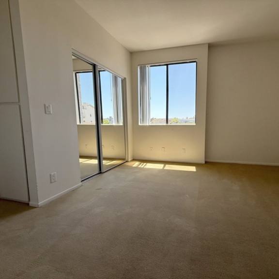 Thumbnail 32 of 54 A room with a carpeted floor, two windows, and a sliding glass door.