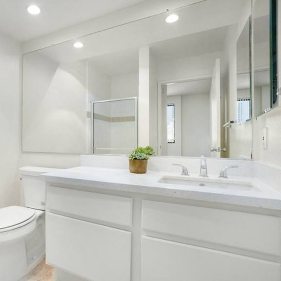Thumbnail 39 of 44 A white bathroom with a toilet, sink, and mirror.