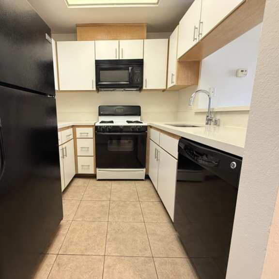 Thumbnail 18 of 39 A kitchen with black appliances and white cabinets.
