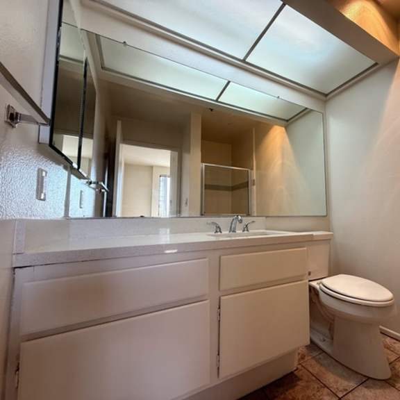 Thumbnail 32 of 39 A bathroom with a toilet, sink, and mirror.