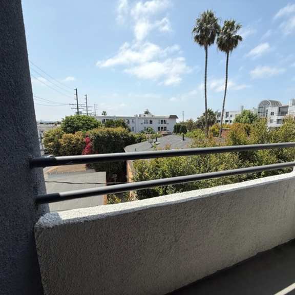 Thumbnail 27 of 39 A balcony with a view of palm trees and buildings.