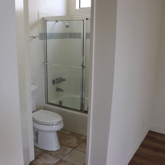 Thumbnail 23 of 30 A white toilet sits in a bathroom next to a walk-in shower.