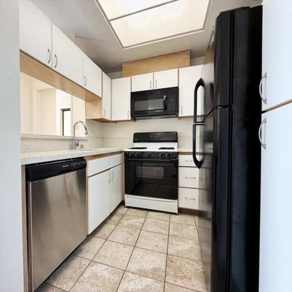 Thumbnail 5 of 19 A kitchen with black appliances and white cabinets.
