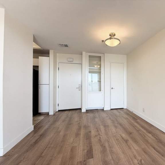 Thumbnail 12 of 19 A room with white walls and wooden flooring with a light fixture on the ceiling.