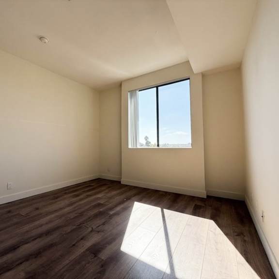 Thumbnail 16 of 19 A room with a window and wooden flooring.