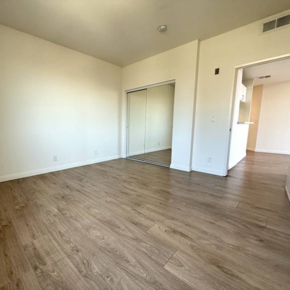 Thumbnail 28 of 54 A room with wood flooring and a glass door.