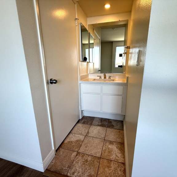 Thumbnail 53 of 54 A bathroom with a white vanity and a mirror.