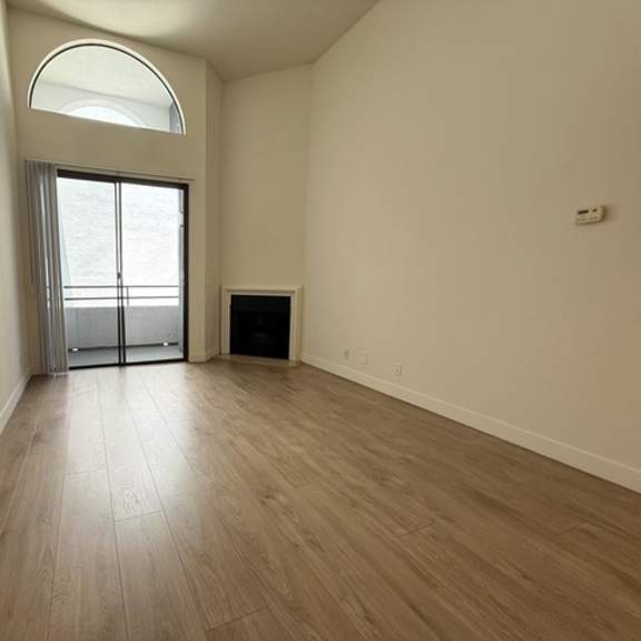 Thumbnail 18 of 19 A room with a wooden floor and a large window with a sliding glass door.