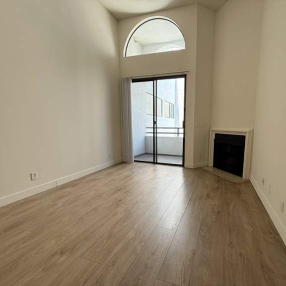 Thumbnail 16 of 19 A room with a wooden floor and a large arched window.
