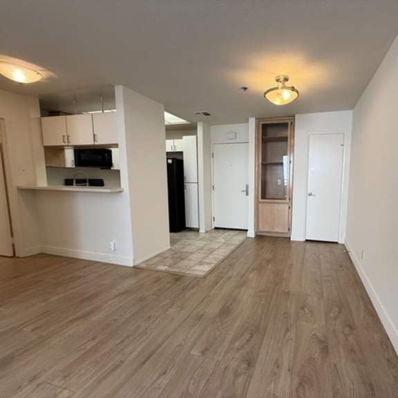 Thumbnail 10 of 19 A spacious room with wooden flooring and white walls.