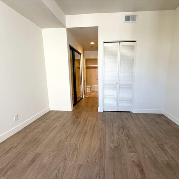 Thumbnail 4 of 19 A room with a white door and wooden flooring.