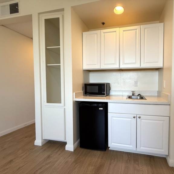 Thumbnail 7 of 16 A kitchen with white cabinets and a black trash can.