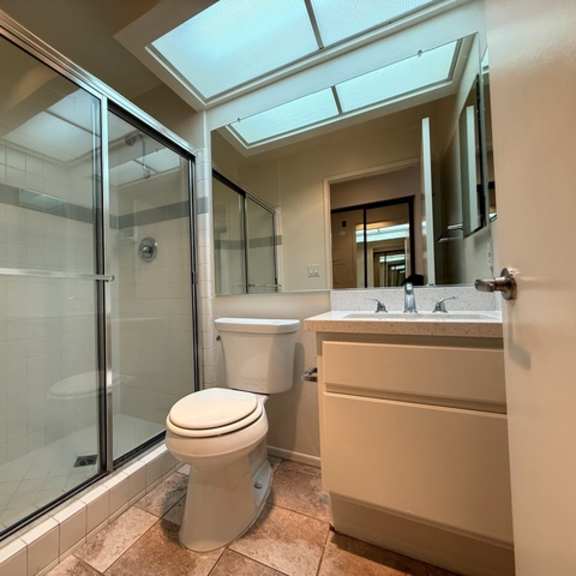 Thumbnail 12 of 16 A bathroom with a toilet, sink, and glass shower.